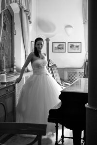 Fekete fehér fotó egy menyasszonyról egy zongora előtt