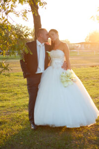 Fiatal pár esküvői ruhában összebújik a naplementében