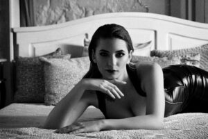 Fekete fehér fotó egy ágyon hason fekvő fiatal lányról.