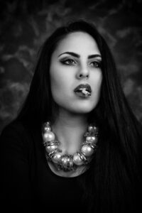 Fekete fehér portré egy fiatal lányról, cigarettával a szájában, vastag nyaklánccal a nyakában.